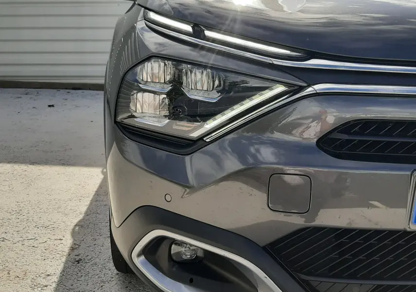Gros plan sur l'avant droit gris d'une Citroën C4 2024, mettant en valeur les phares LED et la calandre moderne.