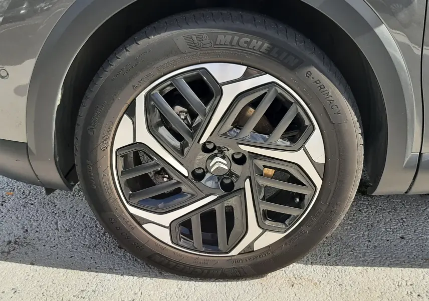 Gros plan sur la roue avant gauche d'une Citroën C4 gris 2024 avec jante alliage bicolore et pneu Michelin.