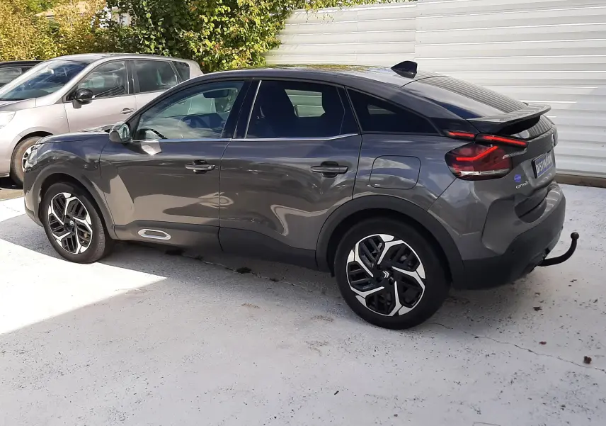 Vue latérale droite d'une Citroën C4 gris 2024 avec jantes bi-ton et toit noir, stationnée en extérieur.