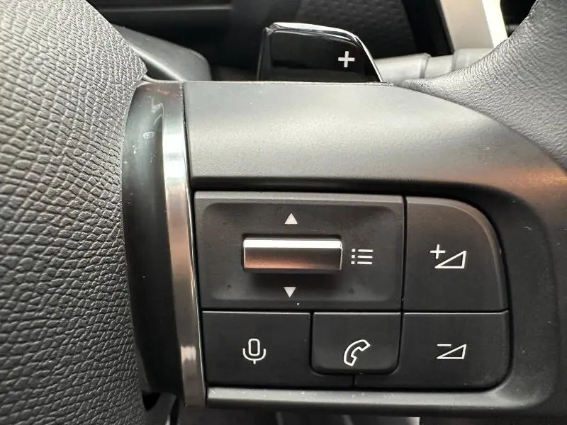 Gros plan sur les commandes au volant du Citroën C4 X 2025 gris Mercury, avec boutons de volume et téléphone visibles.