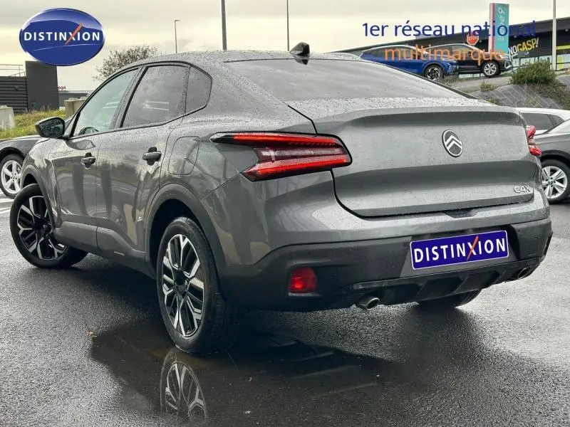 Vue 3/4 arrière droite d'une Citroën C4 X gris Mercury 2025 avec feux arrière LED et double sortie d'échappement visible.