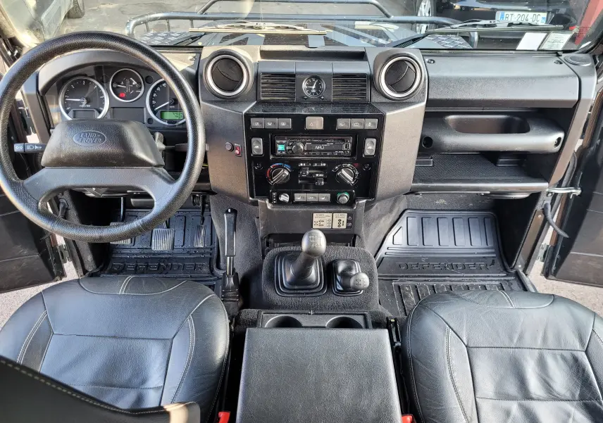 Vue intérieure du tableau de bord et des sièges en cuir noir du Land Rover 110 Defender Edition Limiter gris avec boîte manuelle.