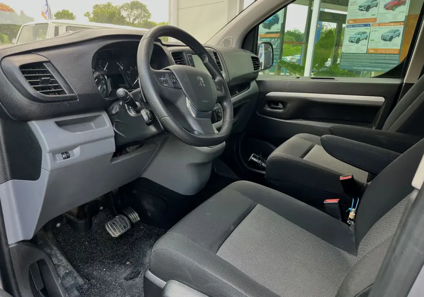 Vue intérieure côté conducteur du Peugeot Expert Cabine Approfondie gris, tableau de bord et sièges en tissu noir visibles.