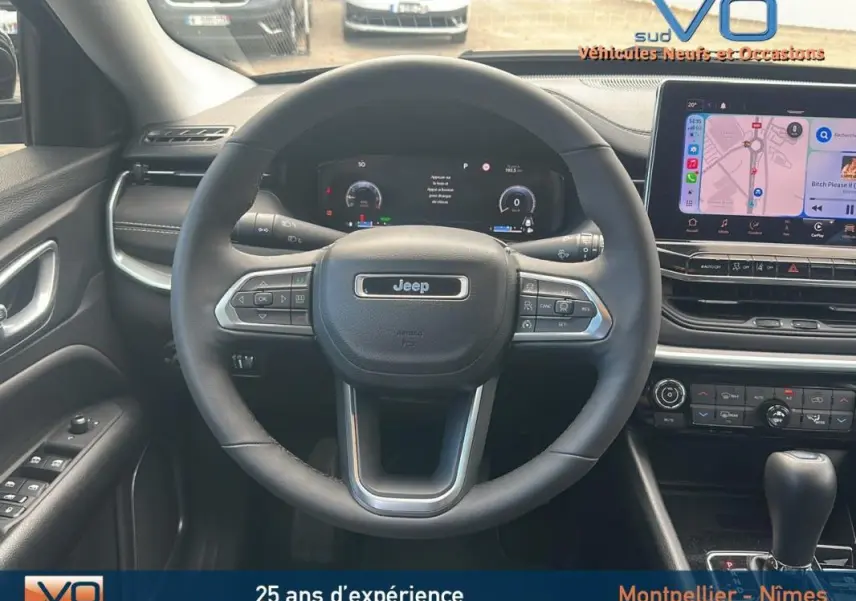 Vue intérieure centrée sur le volant Jeep Compass 2023 avec écran tactile et commandes au volant visibles.