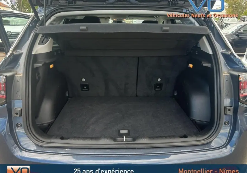 Coffre ouvert en vue arrière d'un Jeep Compass bleu 2023 avec intérieur noir et hayon relevé.