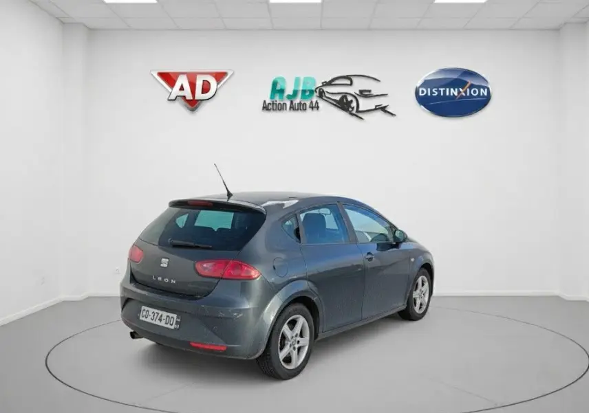 Vue 3/4 arrière droite d'une SEAT LEON noire 2013 avec jantes alu 16 pouces dans un studio blanc.