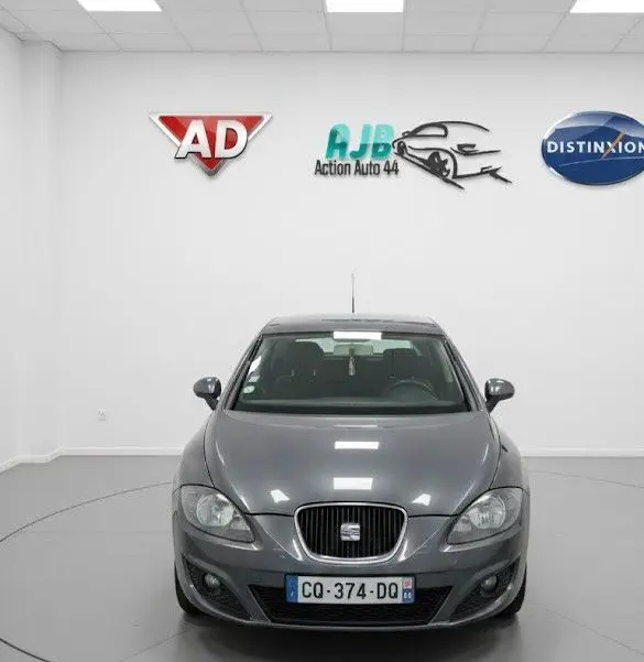 Vue avant d'une SEAT LEON noire stationnée en intérieur, avec calandre caractéristique et phares halogènes visibles.