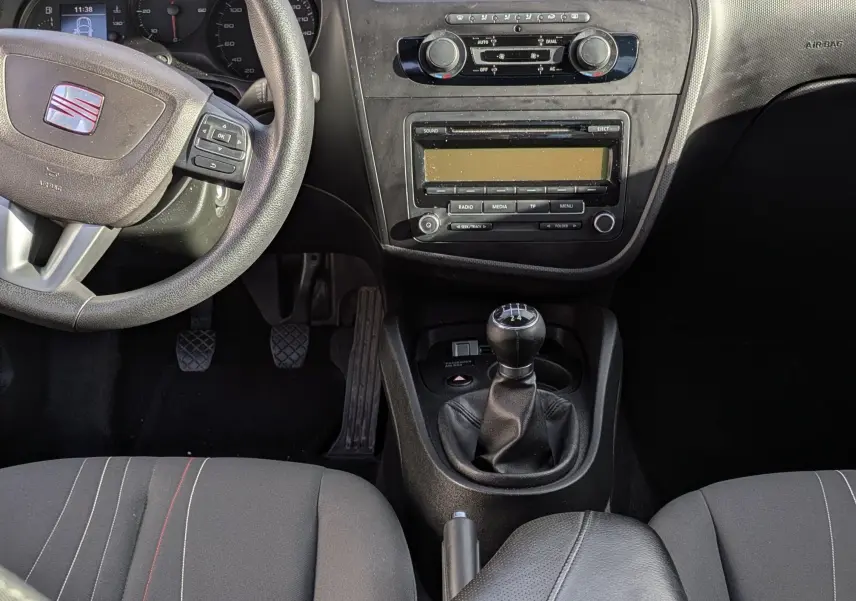 Vue intérieure avant du tableau de bord et volant cuir noir de la SEAT LEON II 1.6 TDi avec levier de vitesse manuel.