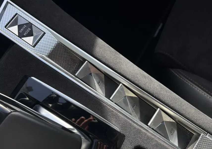 Gros plan sur la console centrale en Alcantara noir profond avec boutons de commande à motifs géométriques du DS7 1.6 E-Tense 2024.