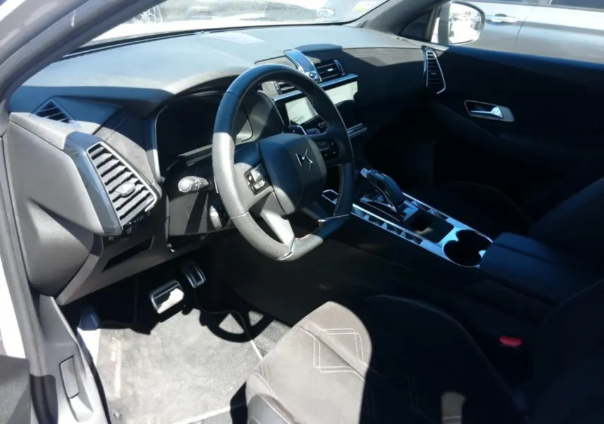 Vue intérieure côté conducteur du DS7 2024, volant cuir noir, console centrale brillante et sellerie Alcantara noire.