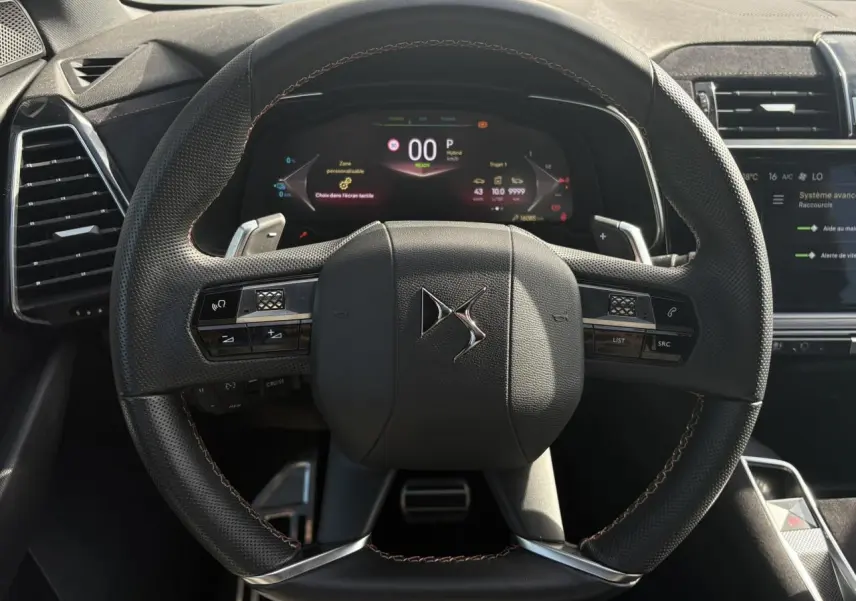 Vue frontale du volant en cuir noir perforé avec surpiqûres Carmin et Or du DS7 1.6 E-Tense 2024, tableau de bord numérique visible.