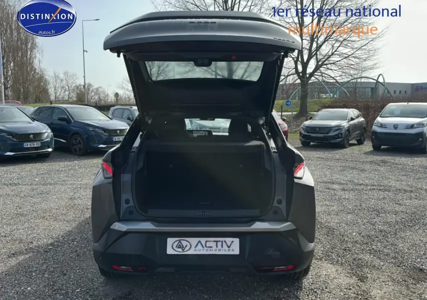 Vue arrière d'un Peugeot 3008 gris titane 2025 avec coffre ouvert sur un parking extérieur.