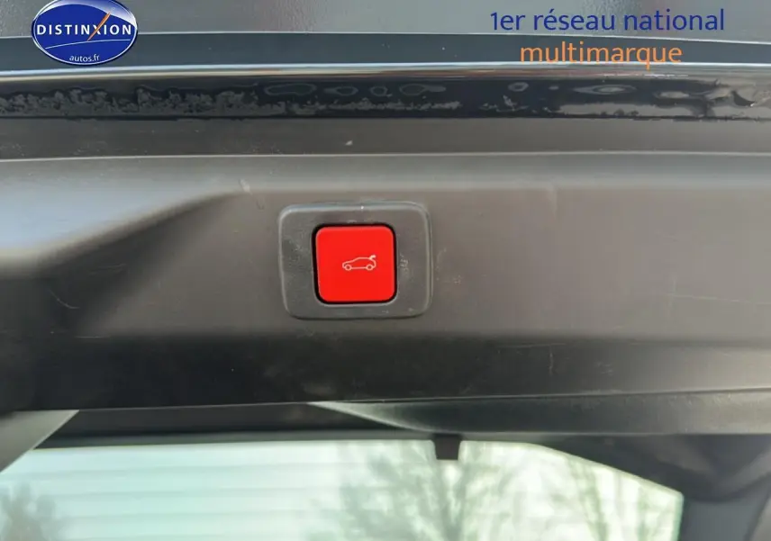 Bouton rouge d'ouverture électrique du coffre visible sur le hayon d'un Peugeot 3008 gris titane.