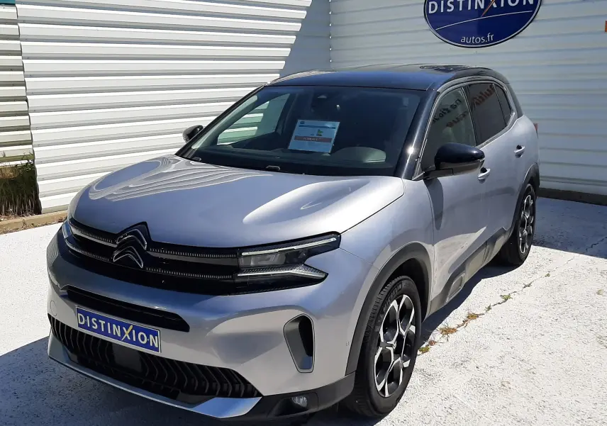Citroën C5 Aircross Hybrid gris acier avec toit noir, vue 3/4 avant droit, sur parking extérieur lumineux.