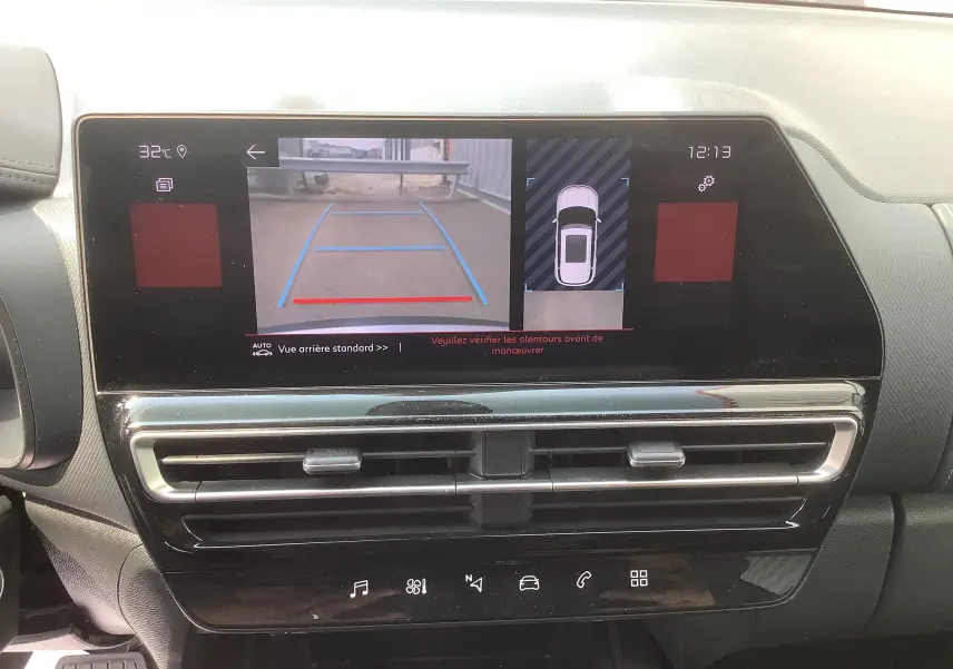 Vue rapprochée de l’écran central du tableau de bord affichant la caméra de recul et l’aide au stationnement du Citroën C5 Aircross gris acier toit noir.