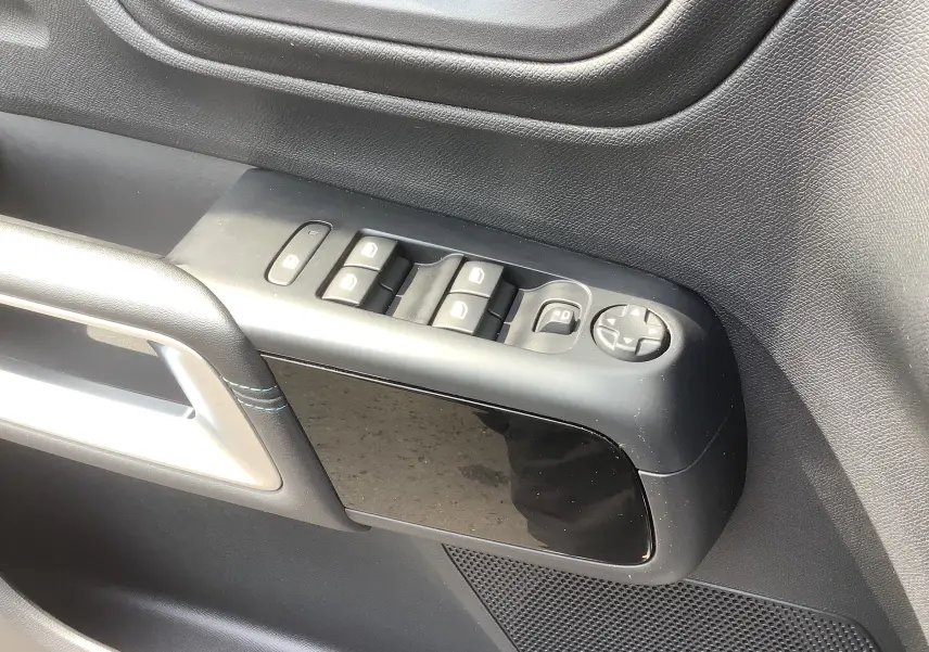 Vue rapprochée de la commande des vitres côté conducteur du Citroën C5 Aircross Hybrid gris acier avec accoudoir noir et surpiqûres bleues.