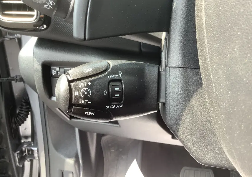 Gros plan sur la commande de régulateur de vitesse noire dans l’habitacle gris foncé du Citroën C5 Aircross Hybrid 2024.