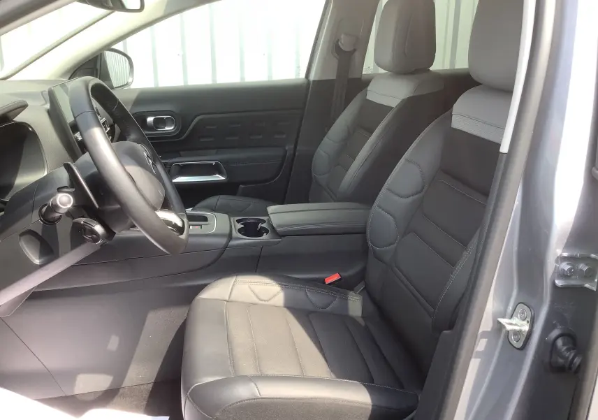 Vue intérieure côté conducteur du Citroën C5 Aircross Hybrid 136 gris acier, sièges noirs en cuir et tissu, tableau de bord moderne.