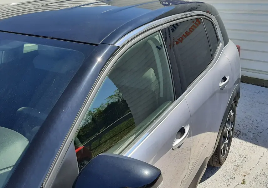 Vue côté gauche en 3/4 arrière d’un Citroën C5 Aircross Hybrid 136 e-DCS6 Max gris acier avec toit noir brillant.