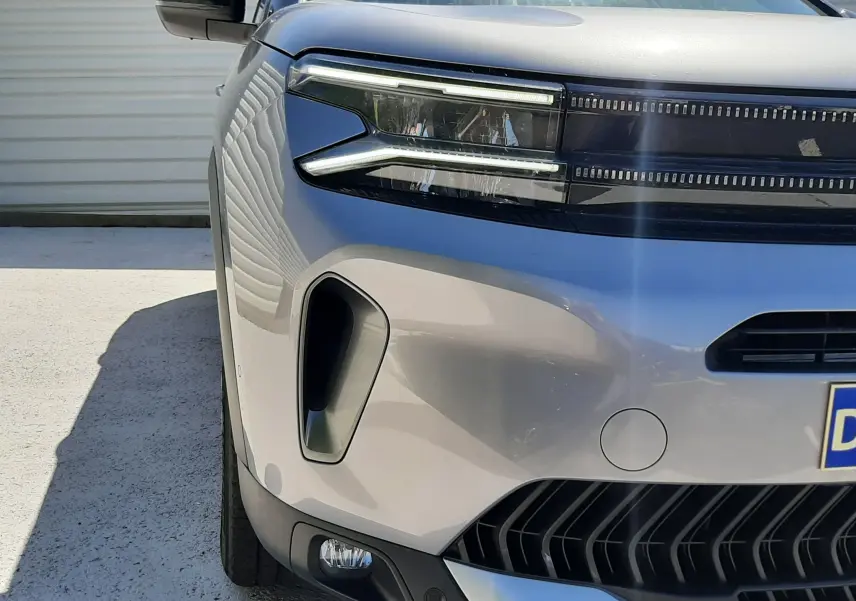 Gros plan sur l'avant gauche du Citroën C5 Aircross Hybrid 136 e-DCS6 Max gris acier avec toit noir, mettant en valeur ses phares LED distinctifs.