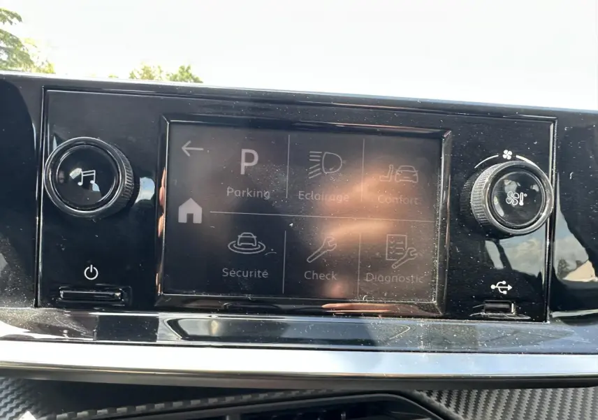 Écran tactile central de la Peugeot 208 2021 avec commandes de climatisation et options affichées en mode parking.