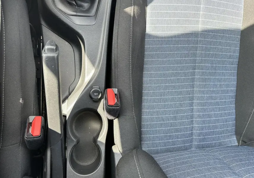 Vue rapprochée de la console centrale et des sièges avant tissu gris à rayures de la Peugeot 208 blanche.