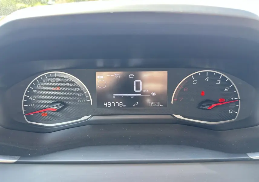 Vue rapprochée du tableau de bord numérique du Peugeot 208 blanc, affichant la vitesse à zéro et le compteur kilométrique.