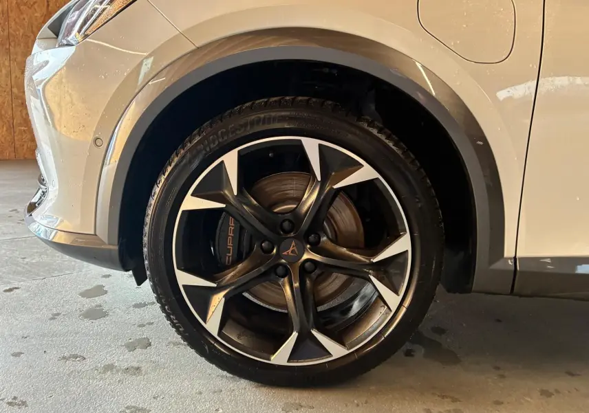 Gros plan sur la roue avant droite gris métallisé d'une CUPRA Formentor 1.4 E-HYBRID 245 avec jante noire et argentée.