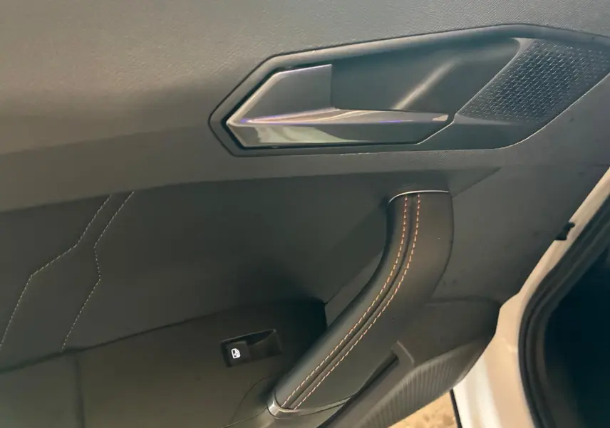 Poignée de porte intérieure avec surpiqûres orange sur tissu noir, côté gauche d'une CUPRA Formentor gris 2024.
