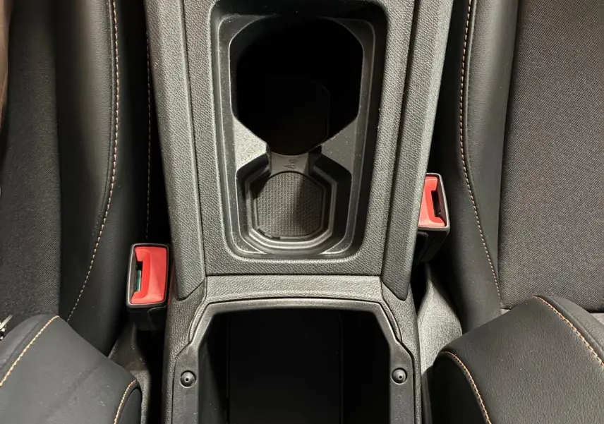 Vue plongeante sur la console centrale noire du Cupra Formentor 1.4 E-HYBRID 2024, avec porte-gobelets et prise 12V visible.