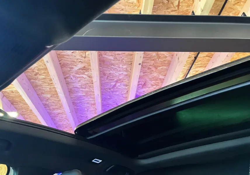Toit ouvrant panoramique ouvert vu de l'intérieur d'une CUPRA Formentor gris, avec plafond en bois visible à l'extérieur.