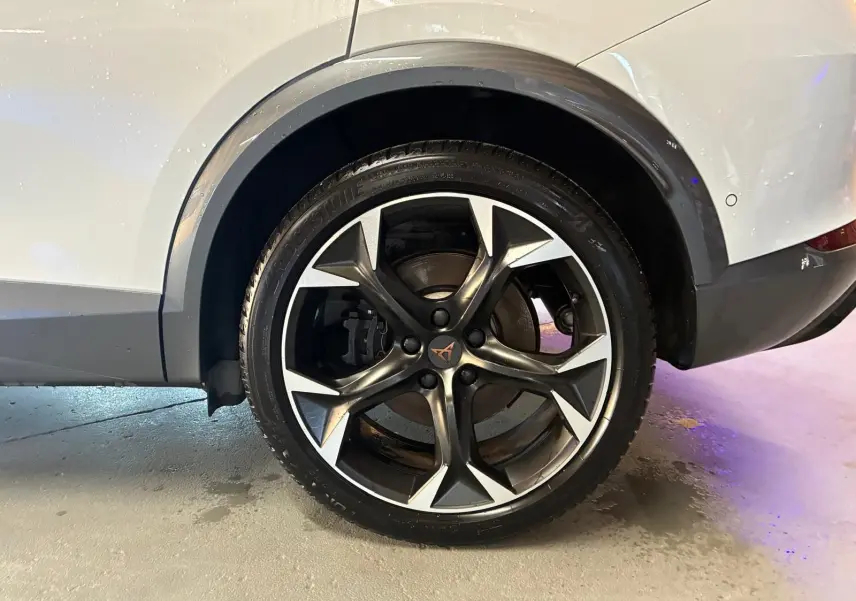 Gros plan sur la roue arrière droite d’un CUPRA Formentor gris 2024, mettant en valeur la jante alliage noire et argentée au design sportif.