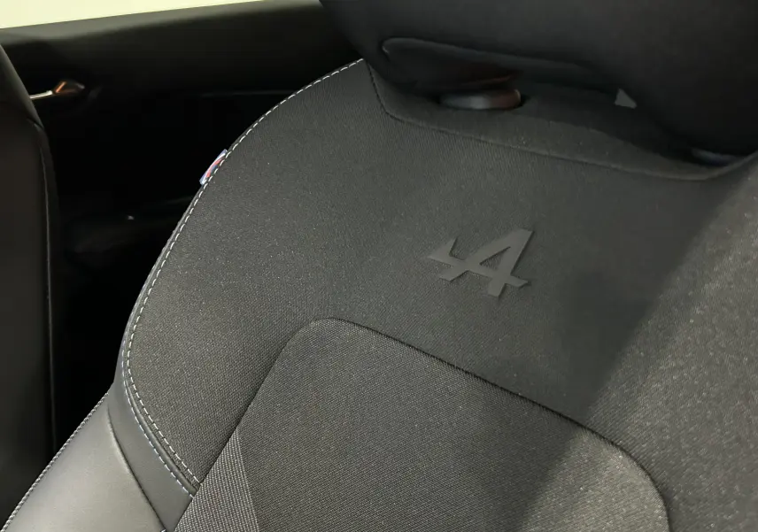 Détail du siège avant noir avec logo Alpine embossé, intérieur du Renault Captur II Ph.2 blanc nacré.