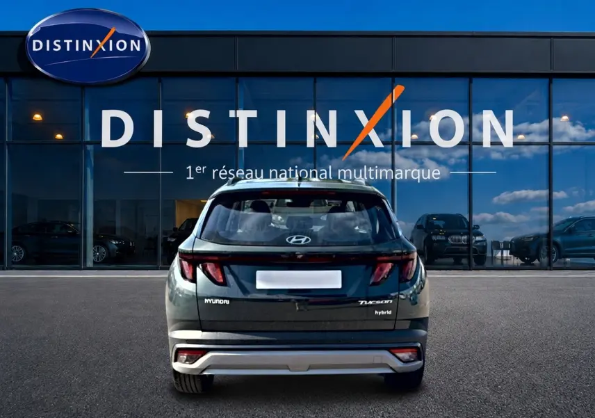 Vue arrière d'un Hyundai Tucson hybride vert 2026 garé devant une vitrine avec logo Distinxion.