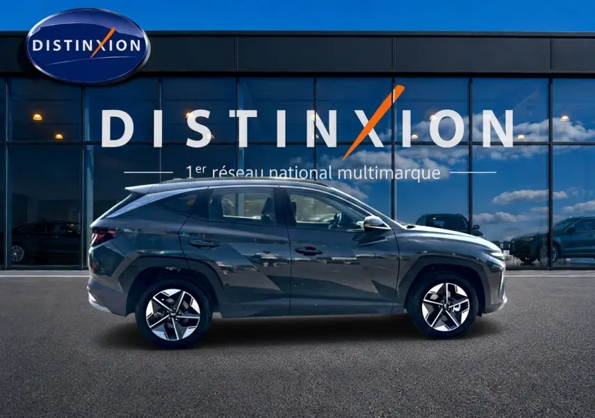 Profil côté gauche du Hyundai Tucson 2026 vert foncé avec jantes alliage, stationné devant une vitrine Distinxion.