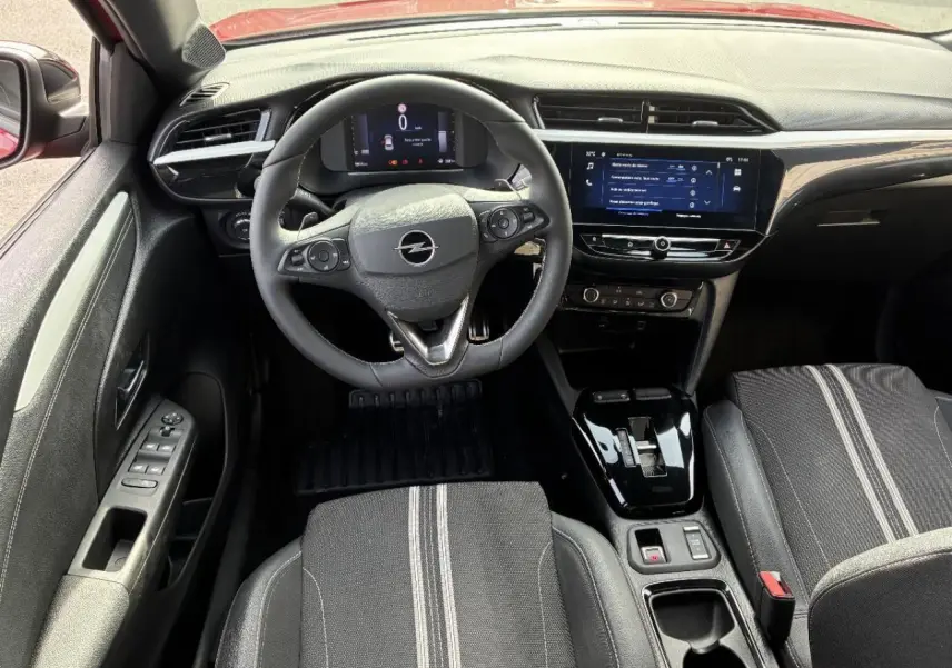 Vue intérieure avant de l’Opel Corsa 1,2 Hybrid 2025, avec volant multifonction, écran tactile et sièges noirs à bandes grises.