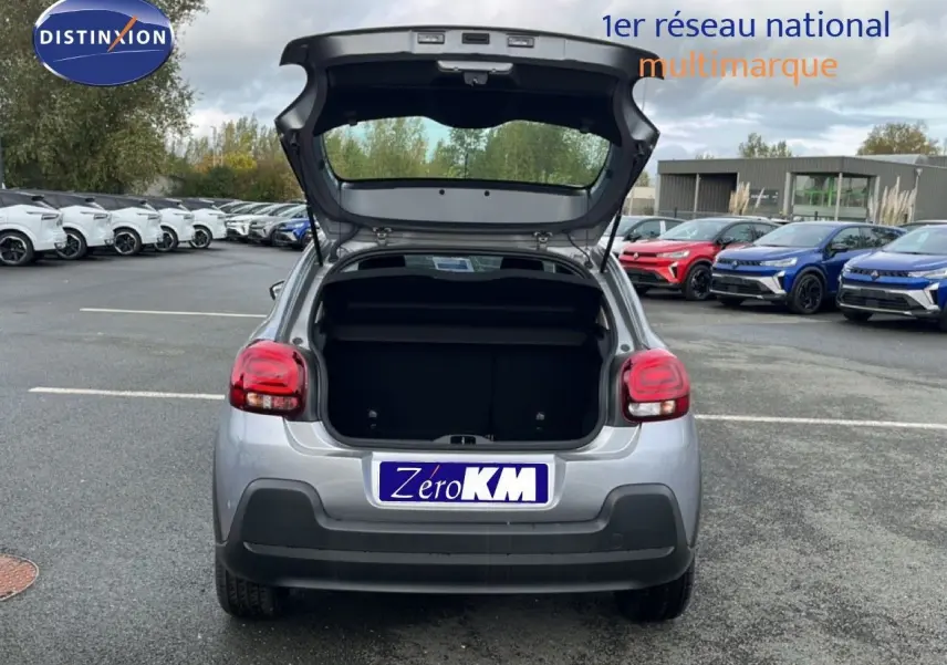 Vue arrière d'une Citroën C3 1.2 PureTech 82ch Plus gris Artense métal avec coffre ouvert sur un parking extérieur.