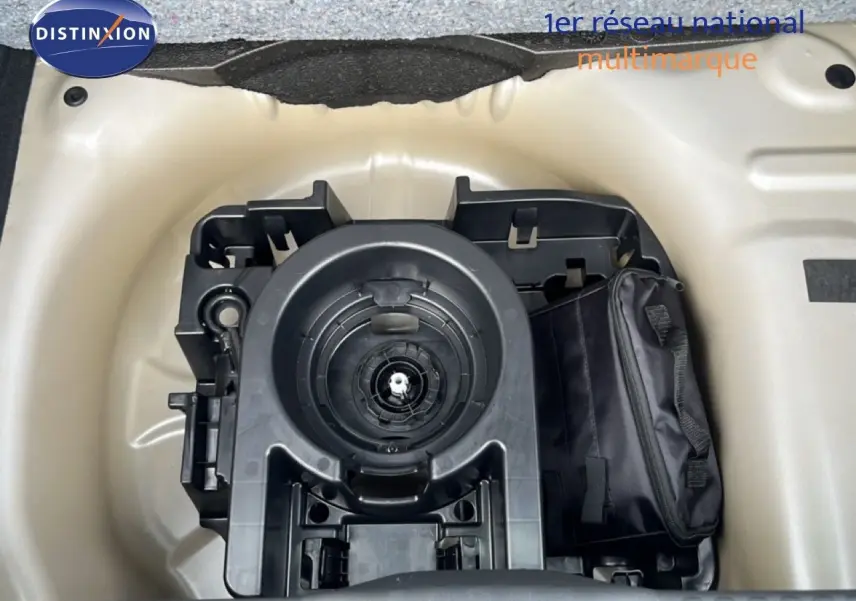 Vue plongeante sur le compartiment de roue de secours d'une Citroën C3 gris Artense métal, avec kit de réparation visible.
