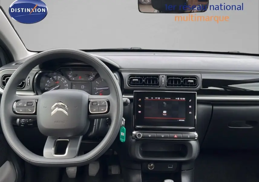 Vue intérieure frontale du tableau de bord de la Citroën C3 2024, avec volant gris et écran tactile central.