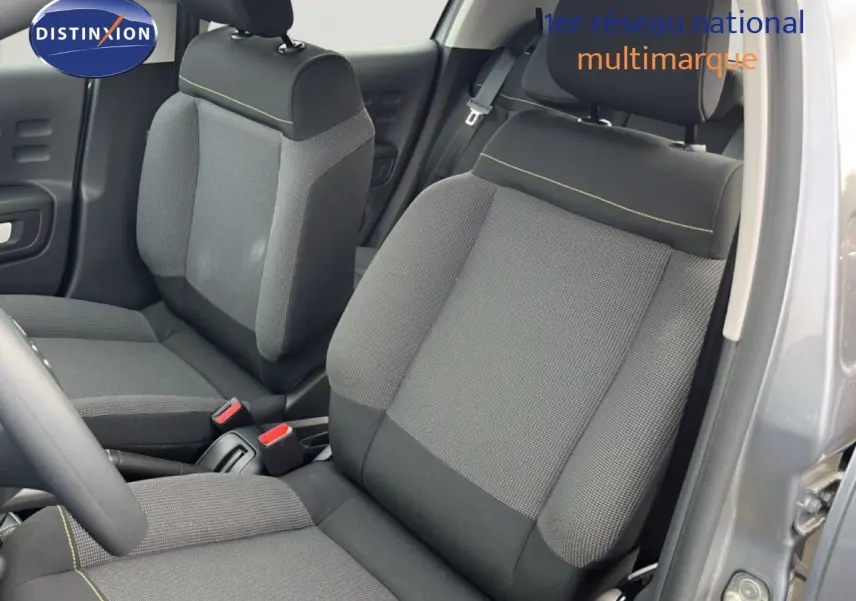 Vue intérieure côté conducteur de la Citroën C3 2024 gris Artense, sièges tissu gris avec surpiqûres jaunes.
