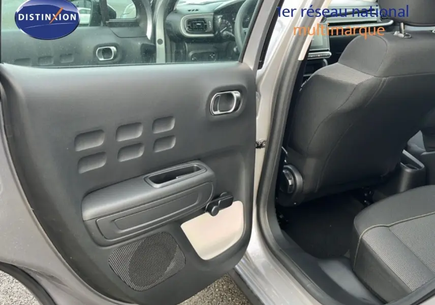 Vue intérieure côté gauche de la porte arrière ouverte d'une Citroën C3 gris Artense 2024, avec sellerie noire et détails clairs.