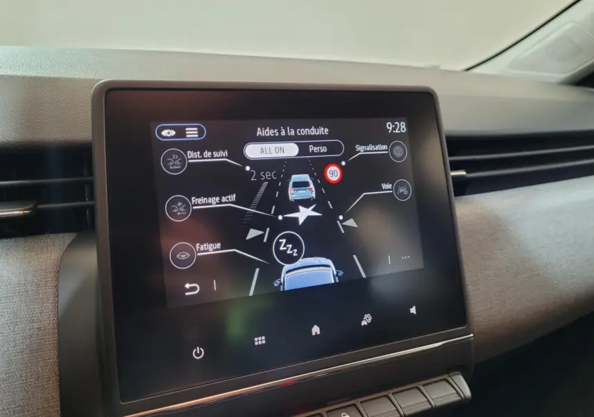 Écran tactile central montrant les aides à la conduite dans l’habitacle clair d’une Renault Clio gris foncé.