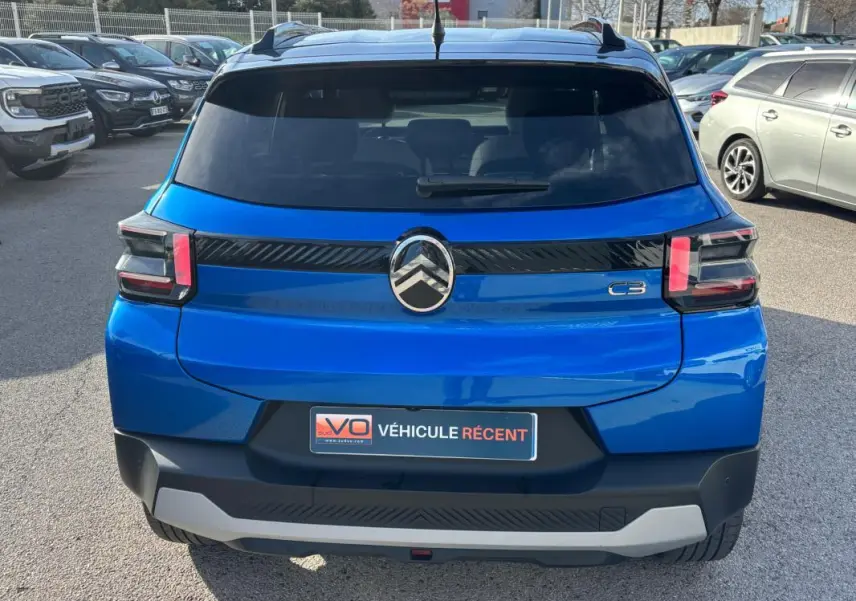Vue arrière d'une Citroën C3 bleu vif 2025 avec barres de toit et feux arrière distinctifs en forme de "C".