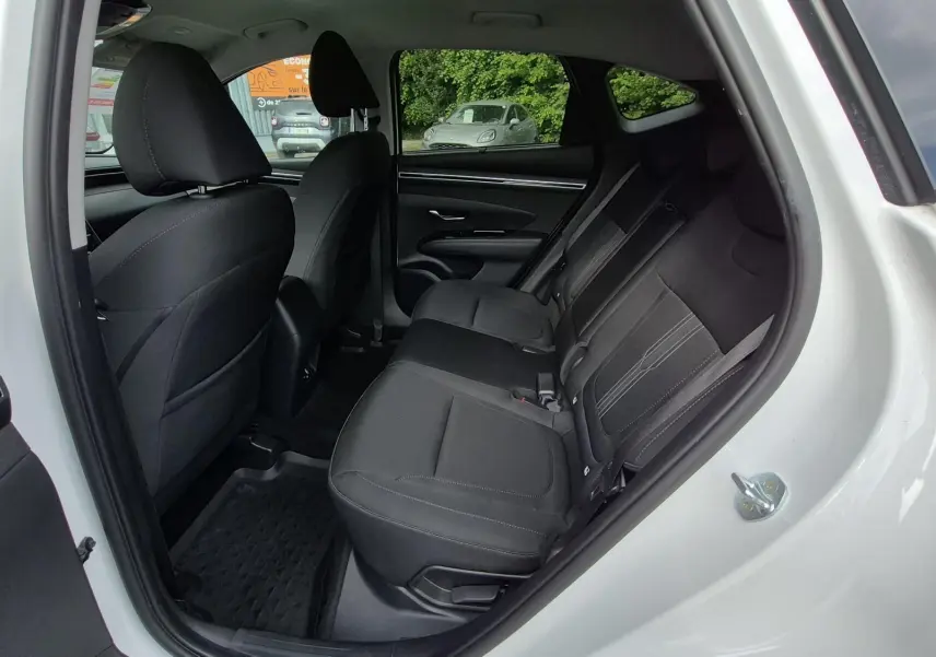 Vue intérieure côté droit sur les sièges arrière noirs en tissu du Hyundai Tucson blanc 2022, porte ouverte.