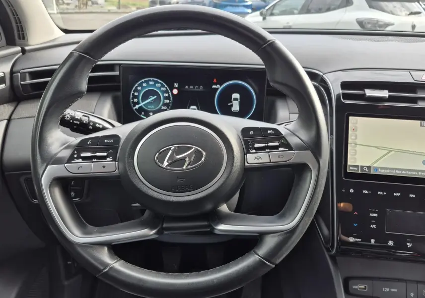 Vue intérieure frontale du volant noir de la Hyundai Tucson 2022 avec tableau de bord numérique et écran tactile GPS.