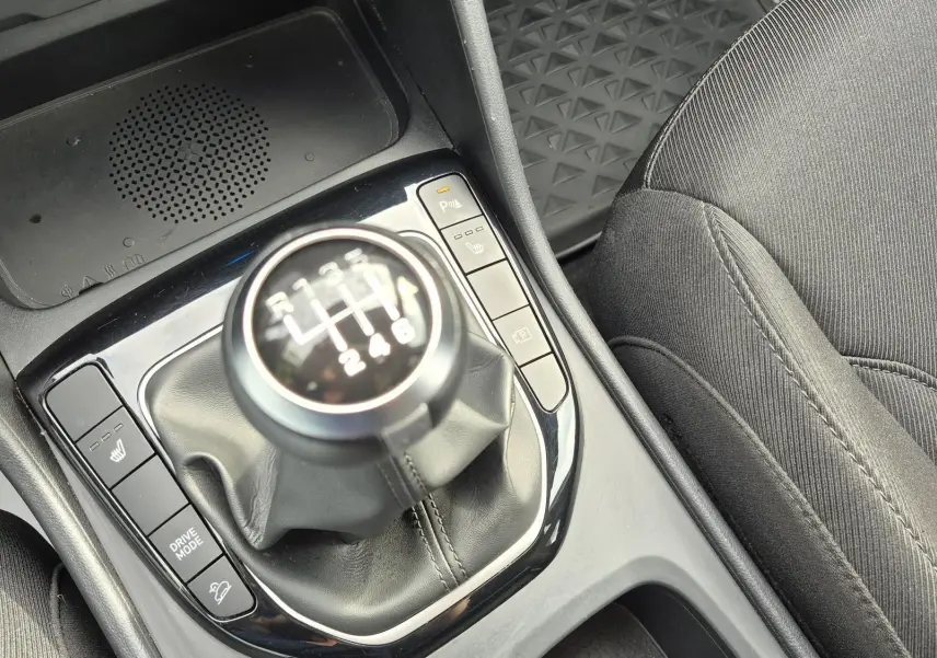 Gros plan sur le levier de vitesses manuel et la console centrale du Hyundai Tucson 1.6 CRDI blanc, avec siège tissu noir visible.