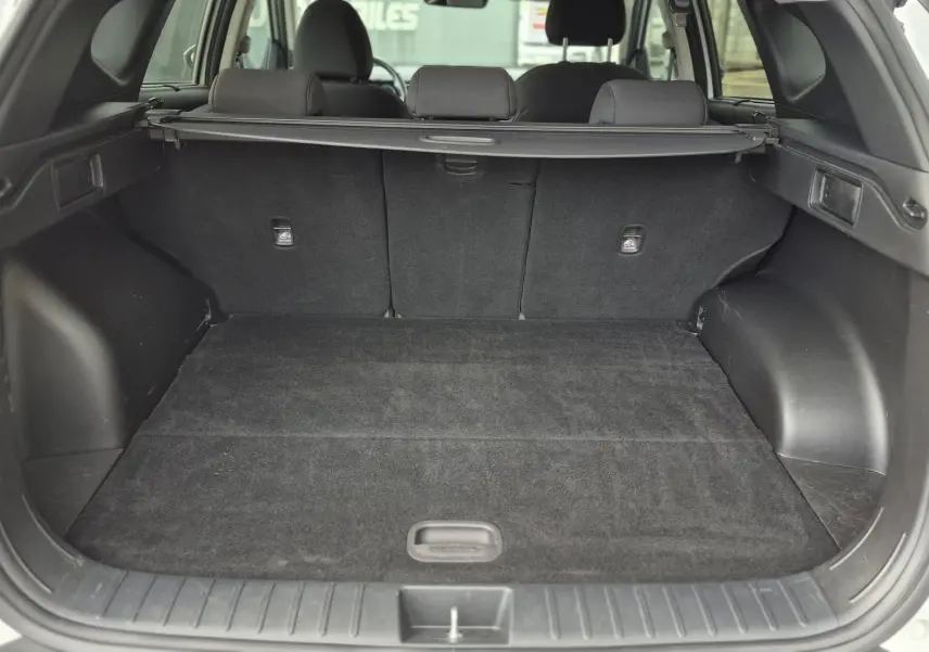 Vue arrière du coffre spacieux et propre d'un Hyundai Tucson blanc 2022, avec banquette arrière et cache-bagages visibles.