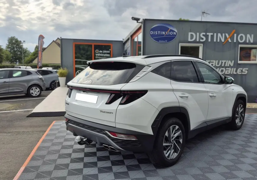 Vue 3/4 arrière droite d’un Hyundai Tucson blanc 2022 avec hayon fermé et feux arrière LED distinctifs.
