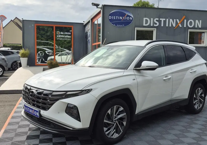 Vue 3/4 avant droit d’un Hyundai Tucson blanc 2022 avec calandre noire et jantes alliage bicolores.