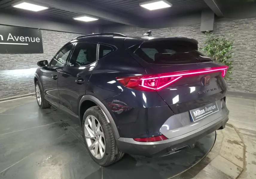 Vue 3/4 arrière du CUPRA Formentor bleu pétrole avec bandeau lumineux arrière LED et jantes alliage 18 pouces.